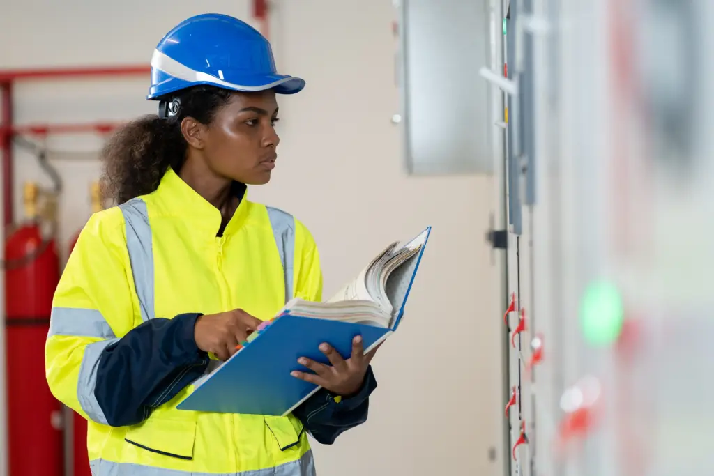 Ingenieurin mit Helm prüft Betriebsanweisungen in einer Industrieanlage.