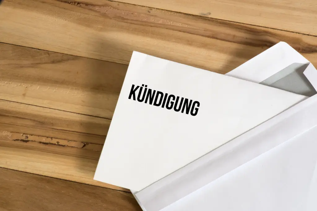 Briefumschlag und ein Brief mit dem Wort "KÜNDIGUNG" auf einem Holztisch.